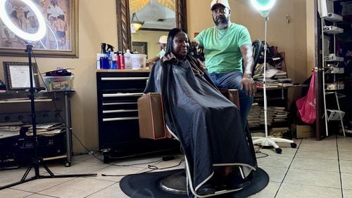 Hair stylist Garrett Milton, 66, tends to a client at his parlor in Fort Valley, the Hidden Image. Milton believes Kamala Harris will win November's presidential election. "You’re getting a Black female running for a Democratic presidency. … I think Black women are going to stand up and fight” for her, he said. (Joe Kovac Jr. / AJC)