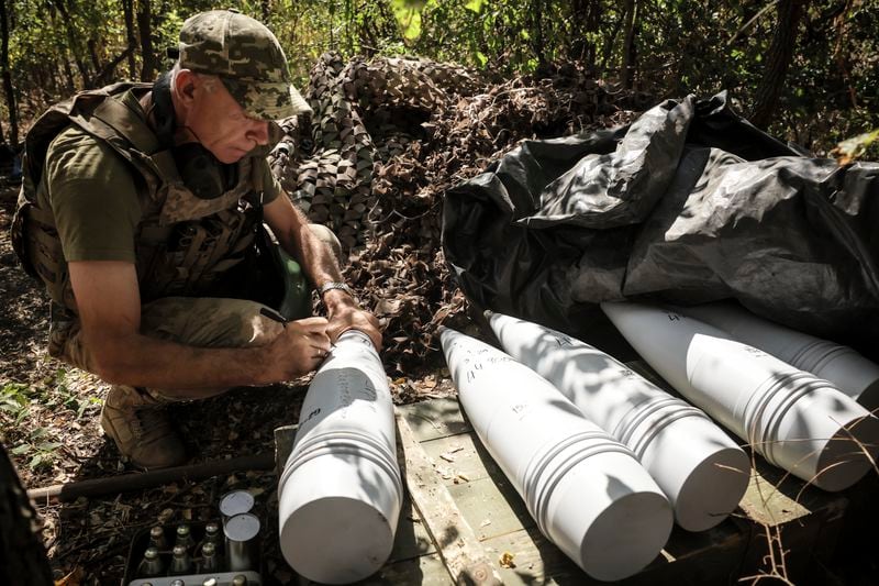 In this photo provided by Ukraine's 24th Mechanised Brigade press service, a soldier of the 24th Mechanised Brigade writes a massage on a Giatsint-S" 152mm self-propelled howitzer prior to firing towards Russian positions near Chasiv Yar town, in Donetsk region, Ukraine, Tuesday, Aug. 20, 2024. (Oleg Petrasiuk/Ukrainian 24th Mechanised Brigade via AP)