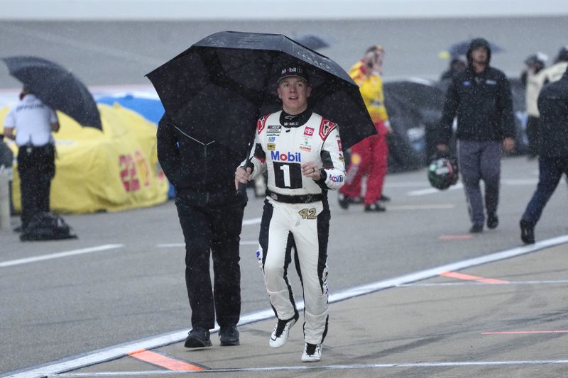 John Hunter Nemechek runs to the team trailer after rain stops a NASCAR Cup Series auto race at Michigan International Speedway, Sunday, Aug. 18, 2024, in Brooklyn, Mich. (AP Photo/Carlos Osorio)