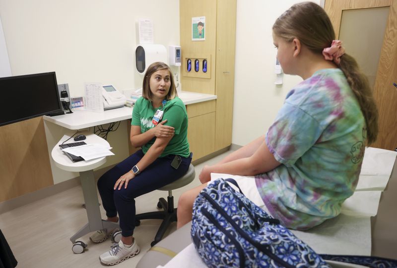 Diabetes Educator Justyna Zabinski, left, talks with 11-year-old Elizabeth Thomas of Duluth, who has Type 1 diabetes, about placing an insulin pump on the back of her arm during a visit at the Children’s Healthcare of Atlanta Center for Advanced Pediatrics, Wednesday, June 12, 2024, in Atlanta. Zabinski is one of several full time diabetes educators who also have Type 1 diabetes. (Jason Getz / AJC)
