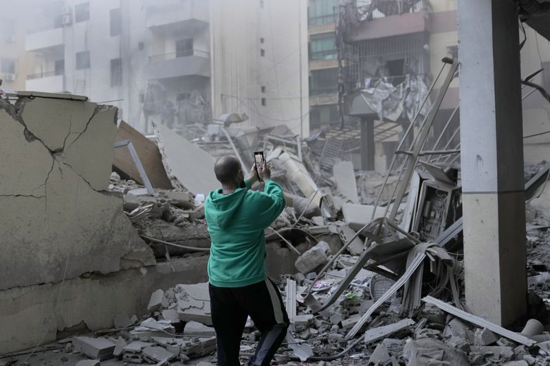 A man takes pictures by his mobile phone of a destroyed building hit by an Israeli airstrike in Dahieh, Beirut, Lebanon, Wednesday, Oct. 2, 2024. (AP Photo/Hussein Malla)