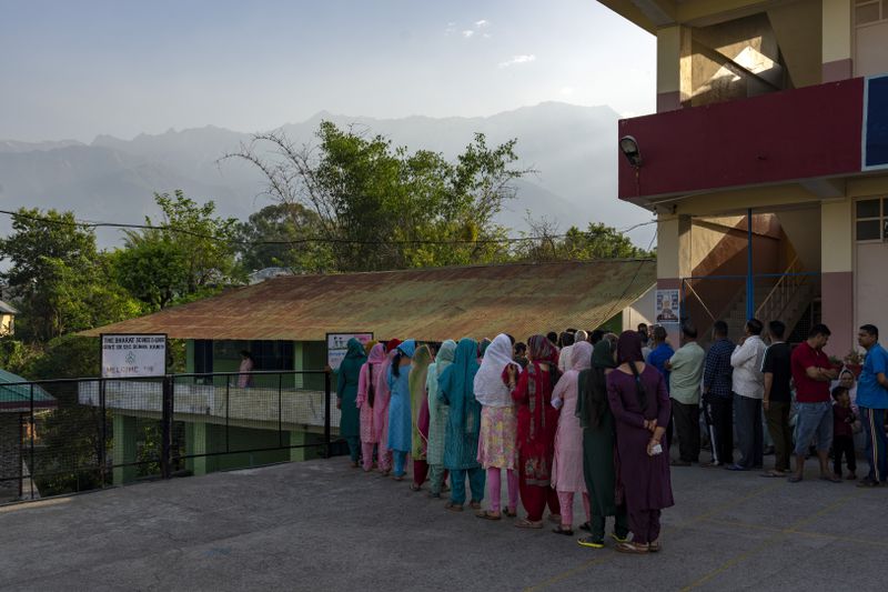 The sun rises behind the Dhauladhar range of the Himalaya as people form queues before voting began in the seventh and last round of polling in India's national election in Dharamshala, India, Saturday, June 1, 2024. (AP Photo/Ashwini Bhatia)
