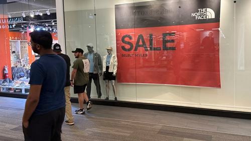 FILE - Shoppers pass a sign trumpeting sales at an outlet mall Wednesday, Sept. 11, 2024, in Lakewood, Colo. (AP Photo/David Zalubowski, File)