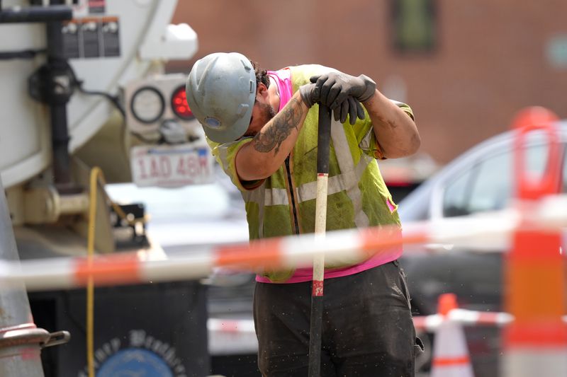 A worker wipes his face while working in temperatures above 90F (32C) at a gas line work site, Thursday, June 20, 2024, on a street in Boston. (AP Photo/Steven Senne)