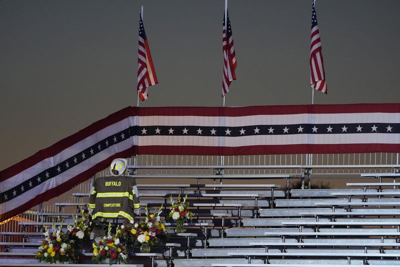 A memorial for firefighter Corey Comperatore, who died as he shielded family members from gunfire, is seen in the bleachers before Republican presidential nominee former President Donald Trump speaks at the Butler Farm Show, the site where a gunman tried to assassinate him in July, Saturday, Oct. 5, 2024, in Butler, Pa. (AP Photo/Alex Brandon)