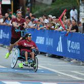 Push assist team Ricardo Aranda and Nick Fragnito win their division of the 55th running of the Atlanta Journal-Constitution Peachtree Road Race in Atlanta on Thursday, July 4, 2024.   (Jason Getz / AJC)