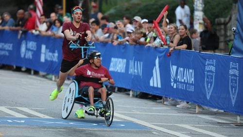 Push assist team Ricardo Aranda and Nick Fragnito win their division of the 55th running of the Atlanta Journal-Constitution Peachtree Road Race in Atlanta on Thursday, July 4, 2024.   (Jason Getz / AJC)