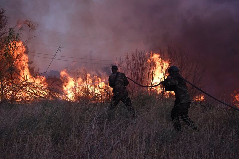 Volunteers try to extinguish the fire in northern Athens, Monday, Aug. 12, 2024, as hundreds of firefighters tackle a major wildfire raging out of control on fringes of Greek capital. (AP Photo/Aggelos Barai)