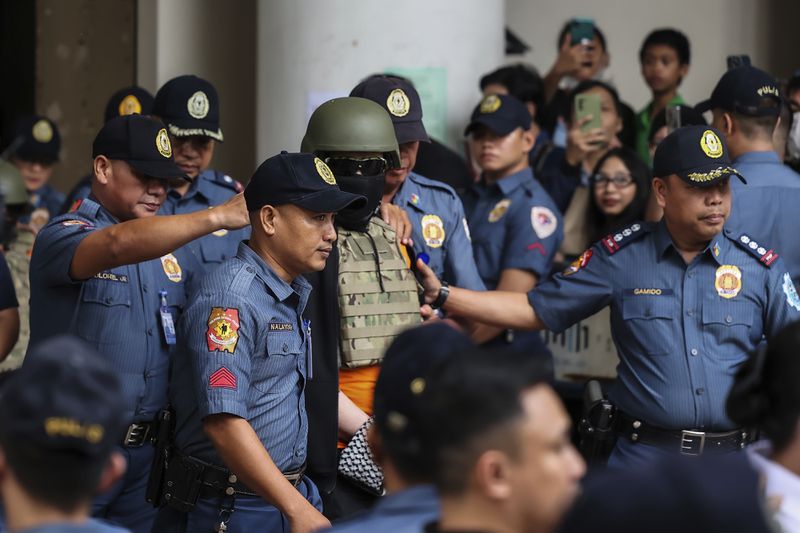 Apollo Carreon Quiboloy, center, wearing a helmet and flak jacket, a Filipino preacher charged with human trafficking, leaves the Pasig Regional Trial Court in Pasig City, Philippines, Friday, Sept. 13, 2024. (AP Photo/Gerard Carreon)