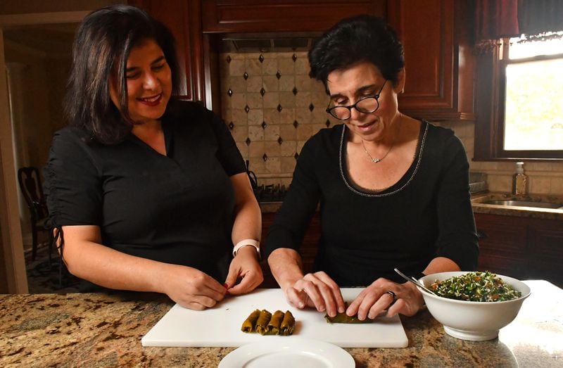 Sisters Farrah Haidar (left) and Hala Yassine make Stuffed Grape Leaves (Warak Enab) in Yassine's Johns Creek kitchen. (Styling by Farrah Haidar and Hala Yassine / Chris Hunt for the AJC)