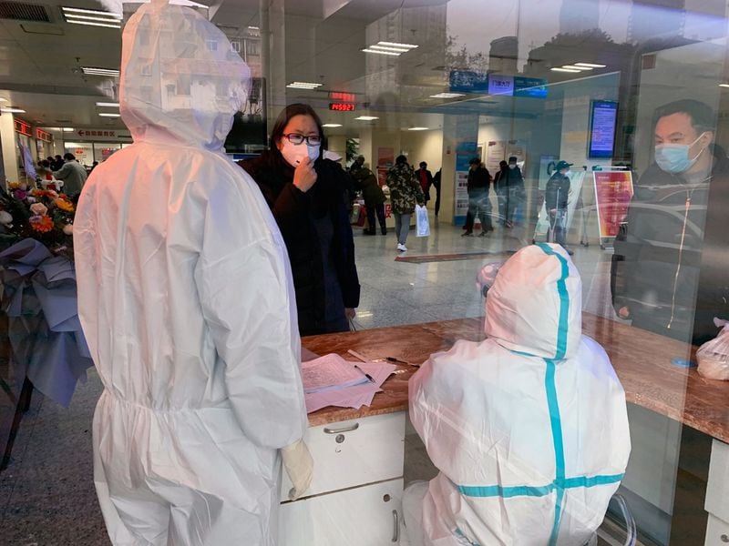 FILE - Hospital personnel wearing protective medical gowns speak to a woman at No. 5 Hospital in Wuhan, China. Some medical workers have scrambled to buy their own protective gear, begged from friends, or relied on donations. (Chris Buckley/The New York Times)