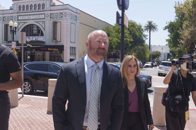 Mathew Bowyer, center left, a Southern California bookbinder, arrives with his attorney, Diane Bass, center right, in federal court in Santa Ana, Calif., Friday, Aug. 9, 2024. (AP Photo/Damian Dovarganes)