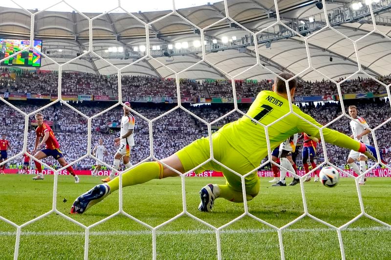 Spain's Dani Olmo, left, scores the opening goal during a quarter final match between Germany and Spain at the Euro 2024 soccer tournament in Stuttgart, Germany, Friday, July 5, 2024. (AP Photo/Manu Fernandez)