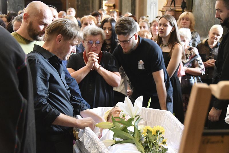 Yaroslav Bazylevych, second left, mourns at the coffins of his family during their funeral service in the Garrison Church in Lviv, Ukraine, Friday, Sept. 6, 2024. Bazylevych's wife Yevgenia and their three daughters - Darina, 18, Emilia, 7, and Yaryna, 21 - were killed in Wednesday's Russian missile attack. (AP Photo/Mykola Tys)