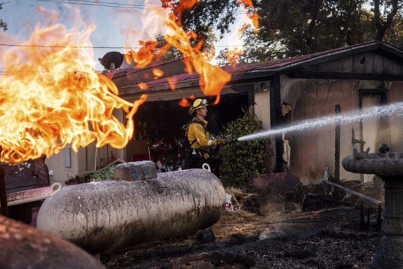 Firefighter Nolan Graham sprays water around a scorched garage as the Boyles fire burns in Clearlake, Calif., on Sunday, Sept. 8, 2024. (AP Photo/Noah Berger)