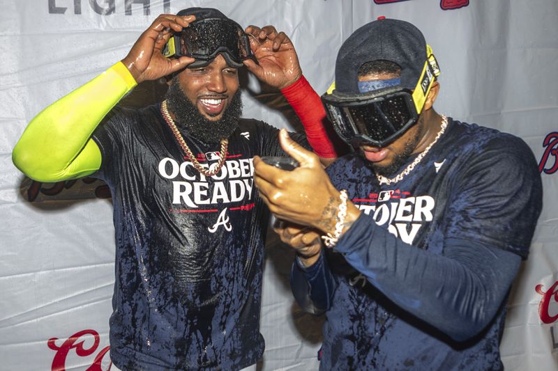 Atlanta Braves designated hitter Marcell Ozuna, left, celebrates with outfielder Ronald Acuña Jr., right, in the locker room after clinching a wild-card playoff berth after the second baseball game of a doubleheader against the New York Mets, Monday, Sept. 30, 2024, in Atlanta. (AP Photo/Jason Allen)