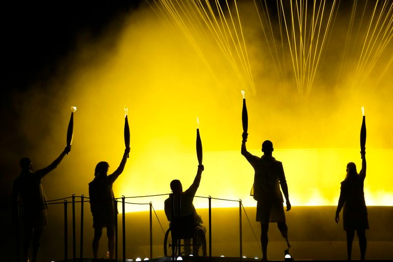 Athletes Charles-Antoine Kouakou, Nantenin Keita, Fabien Lamirault, Alexis Hanquinquant and Elodie Lorandi look up after they lit the cauldron during the Opening Ceremony for the 2024 Paralympics, Wednesday, Aug. 28, 2024, in Paris, France. (AP Photo/Christophe Ena)