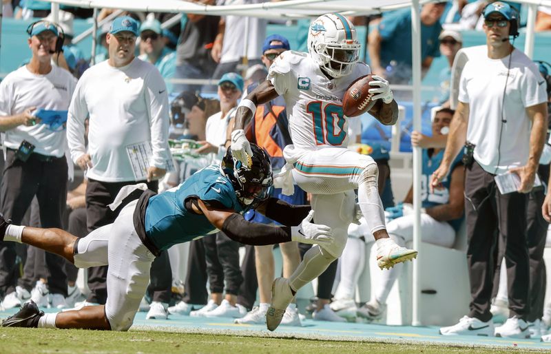 Miami Dolphins wide receiver Tyreek Hill (10) breaks a tackle attempt by Jacksonville Jaguars safety Andre Cisco (5) to score in the second half during an NFL football game at Hard Rock Stadium in Miami Gardens, Florida, on Sunday, Sept. 8, 2024. (Al Diaz/Miami Herald via AP)