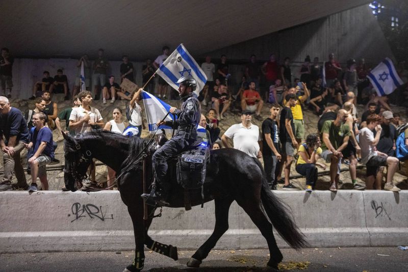 A police officer on a horse moves past a protest calling for a deal for the immediate release of hostages held in the Gaza Strip by Hamas, in Tel Aviv, Israel, Sunday, Sept. 1, 2024. (AP Photo/Ohad Zwigenberg)