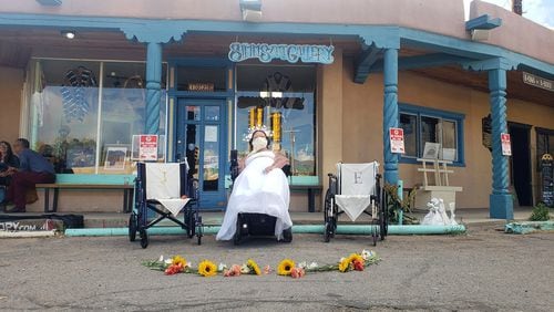 A still from a performance, "REVERENCE: We 3," by Jessica Blinkhorn. In this project, which toured the country, Blinkhorn sat in public spaces that were not wheelchair accessible for three hours each, inviting community members to treat her as an object of reverence with flowers laid before her.