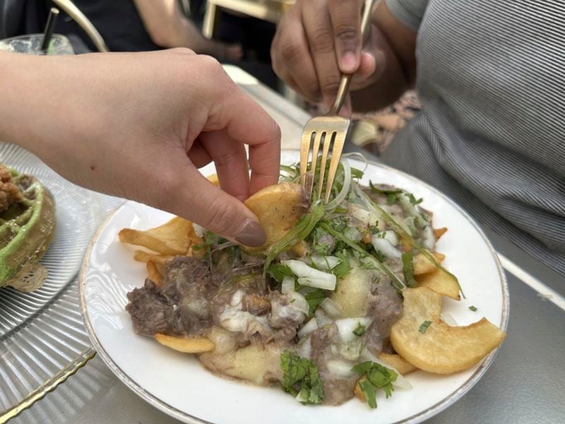 Diners dig into an order of pho poutine -- beef short rib, pho gravy and cheese curds over fries -- at Breaking Dawn restaurant in Los Gatos, Calif., on Sunday, Aug. 4, 2024. (AP Photo/Terry Tang)