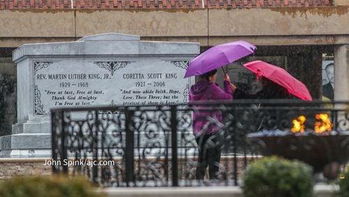 Lina Chinches (left) from the Philippines and her sister, Tita Mclaughlin from Illinois, visit the Martin Luther King Jr. crypt amid light rainfall Friday morning ahead of stronger storms.