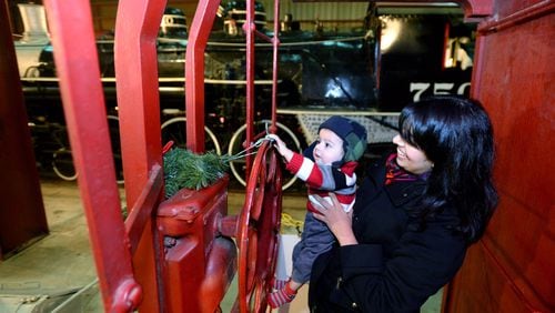 Keri Karim of Duluth holds her 6-month-old son Reza Khoja while he touches one of exhibits at Southeastern Railway Museum in Duluth on Saturday, December 14, 2013.