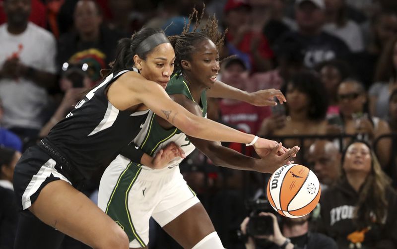Las Vegas Aces center A'ja Wilson, left, and Seattle Storm center Ezi Magbegor (13) vie for the ball during the first half of a WNBA basketball game Wednesday, June 19, 2024, in Las Vegas. (Steve Marcus/Las Vegas Sun via AP)