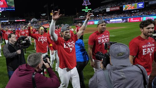 Philadelphia Phillies' Bryce Harper, center left, celebrates after winning a baseball game against the Chicago Cubs to clinch the NL East title, Monday, Sept. 23, 2024, in Philadelphia. (AP Photo/Matt Slocum)