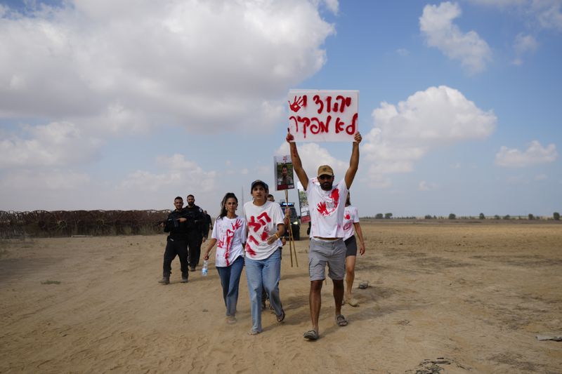 Relatives and friends of hostages held in the Gaza Strip by the Hamas militant group take part in a protest calling for their release as they walk on an area outside the kibbutz Nirim, southern Israel, Thursday, Aug. 29, 2024. (AP Photo/Tsafrir Abayov)