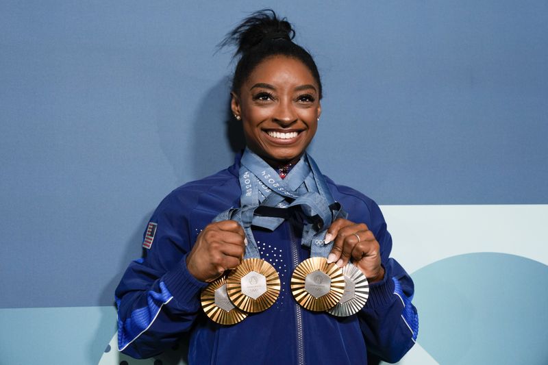 FILE - Simone Biles, of the United States, holds up her medals after the women's artistic gymnastics individual apparatus finals Bercy Arena at the 2024 Summer Olympics, Monday, Aug. 5, 2024, in Paris, France. (AP Photo/Charlie Riedel, File)