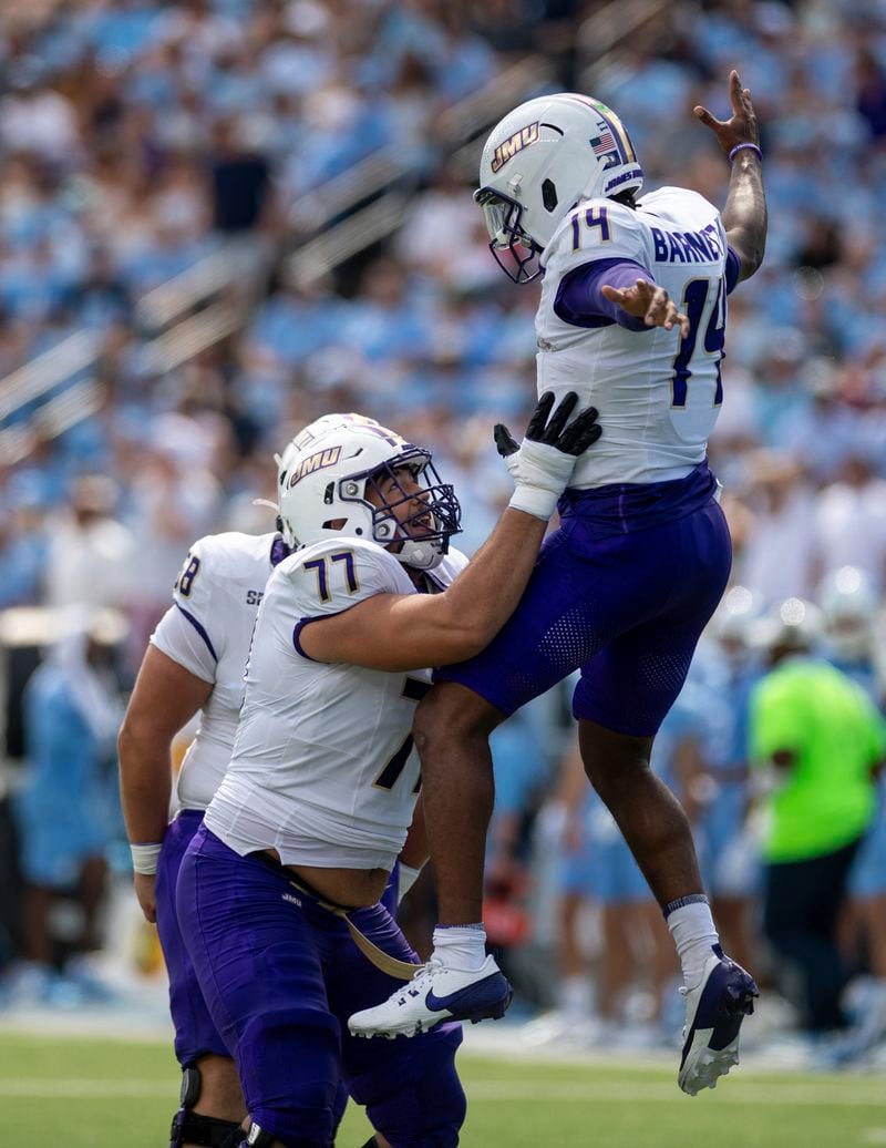 James Madison quarterback Alonza Barnett III (14) celebrates with James Madison offensive lineman Jesse Ramil (77) after throwing a touchdown pass during the first half of an NCAA college football game in Chapel Hill, N.C., Saturday, Sept. 21, 2024. (Daniel Lin/Daily News-Record via AP)