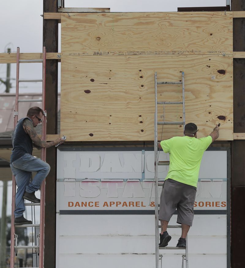 James C. McKenzie, left and Kelly Blanchard cover an electronic sign with plywood ahead of Tropical Storm Francine Monday, Sept. 9, 2024, in Chalmette, La.. (David Grunfeld/The Times-Picayune/The New Orleans Advocate via AP)