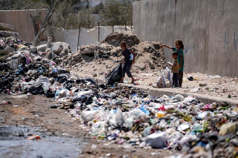 Displaced kids sort through trash at a street in Deir al-Balah, central Gaza Strip, Tuesday, Aug. 27, 2024. (AP Photo/Abdel Kareem Hana)