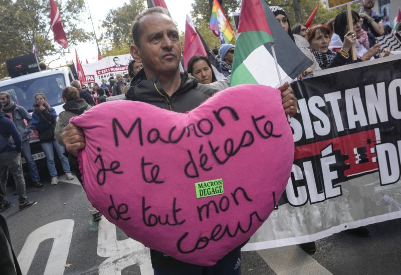 A protester holds a a cushion that reads, "Macron I hate you with all my heart " during rally in support of Palestinian people in Gaza and Lebanon in Paris, Saturday, Oct. 5, 2024. (AP Photo/Michel Euler)