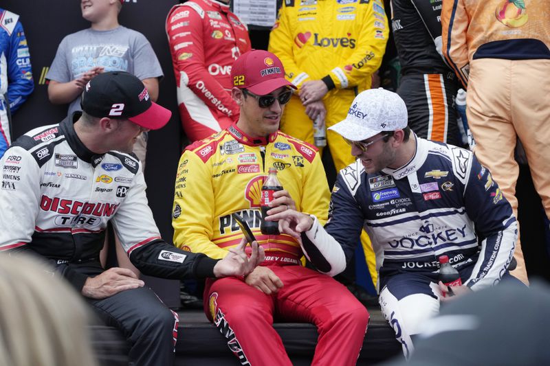 Austin Cendric, left, Joey Logano, center, and Daniel Suarez talk before driver introductions of a NASCAR Cup Series auto race at Michigan International Speedway, Sunday, Aug. 18, 2024, in Brooklyn, Mich. (AP Photo/Carlos Osorio)