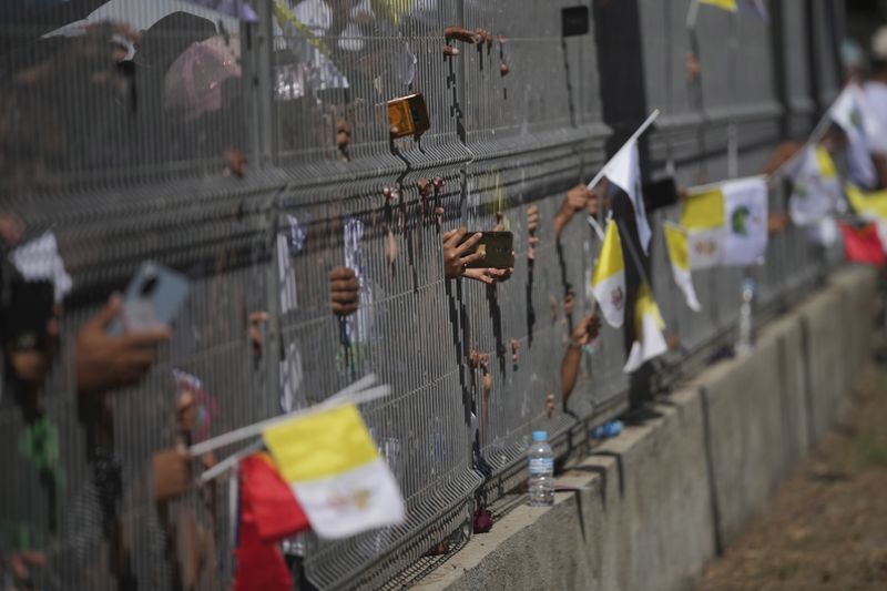 People try to film Pope Francis with their mobile phone through a fence in Dili, East Timor, Monday, Sept. 9, 2024. (AP Photo/Dita Alangkara)