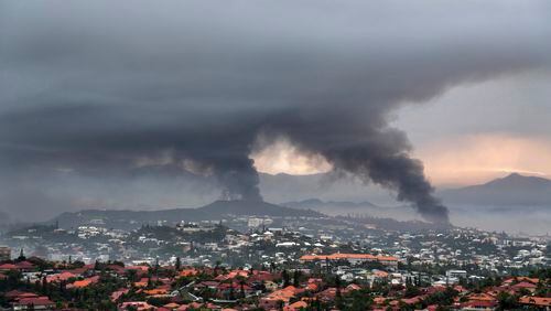 FILE - Smoke rises during protests in Noumea, New Caledonia, Wednesday May 15, 2024. France has imposed a state of emergency in the French Pacific territory of New Caledonia. The French prosecutor for New Caledonia says there's been another shooting death in the riot-hit French Pacific territory, with a police officer taken into custody after using their firearm Friday May 24, 2024 when they were set upon by a group of about 15 people. It comes a day after French President Emmanuel Macron made an emergency round-trip from Paris to de-escalate the violence in New Caledonia where Indigenous Kanak people have long sought independence from France. (AP Photo/Nicolas Job, File)