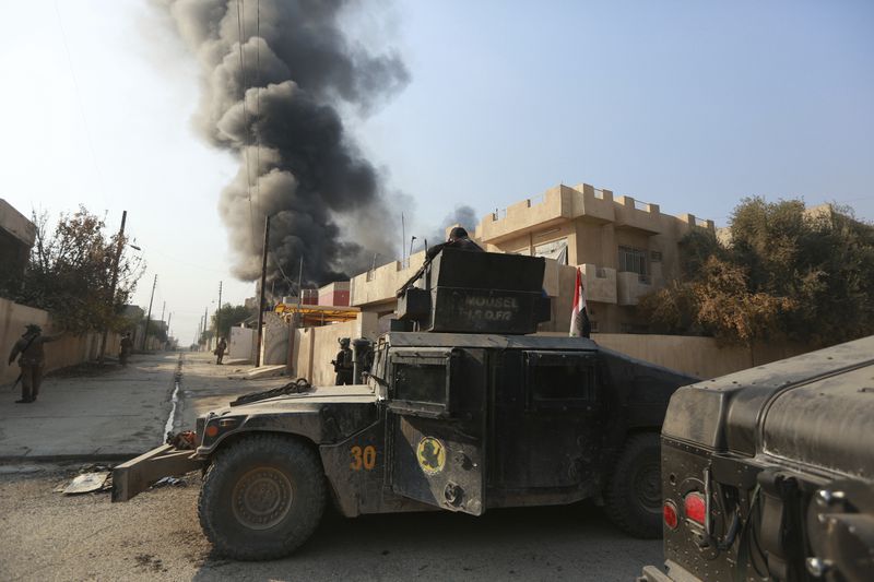 FILE - Smoke rises as Iraq's elite counterterrorism forces fight against Islamic State militants to regain control of al-Bakr neighborhood in Mosul, Iraq, Dec. 12, 2016. Ten years after the Islamic State group declared its caliphate in large parts of Iraq and Syria, the extremists now control no land, have lost many prominent founding leaders and are mostly away from the world news headlines. (AP Photo/Hadi Mizban, File)