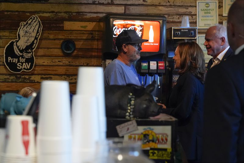 Democratic presidential nominee Vice President Kamala Harris and her running mate Minnesota Gov. Tim Walz talk as they visit SandFly Bar-B-Q in Savannah, Ga., Wednesday, Aug. 28, 2024. (AP Photo/Jacquelyn Martin)