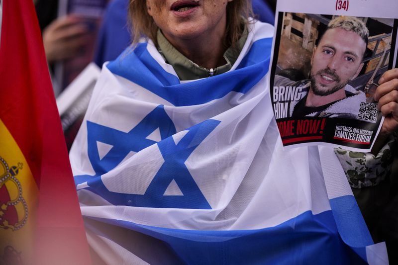 An activist holds a picture of the hostage during a commemoration to mark the one-year anniversary of the Israel Hamas war in Madrid, Spain, Monday, Oct. 7, 2024. (AP Photo/Manu Fernandez)