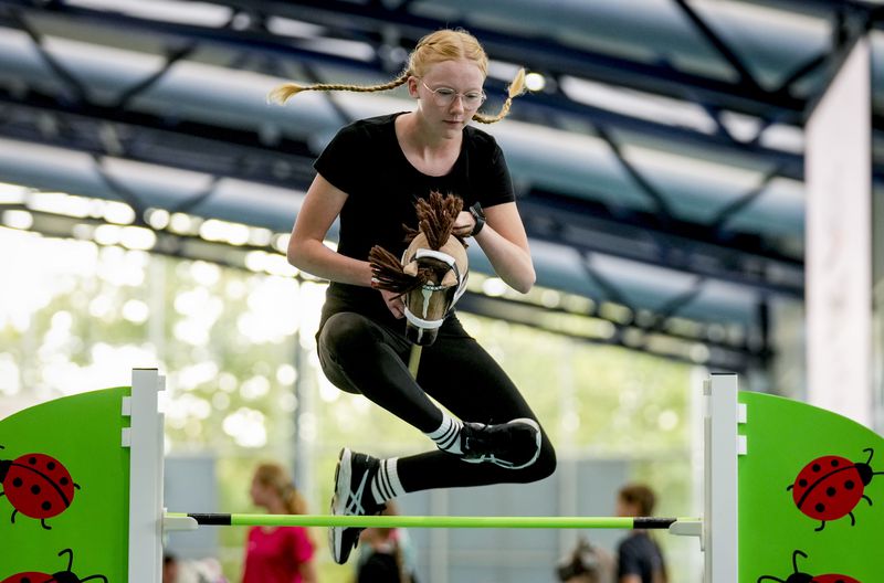 A girl clears the bar during the first German Hobby Horsing Championship in Frankfurt, Germany, Saturday, Sept. 14, 2024. (AP Photo/Michael Probst)