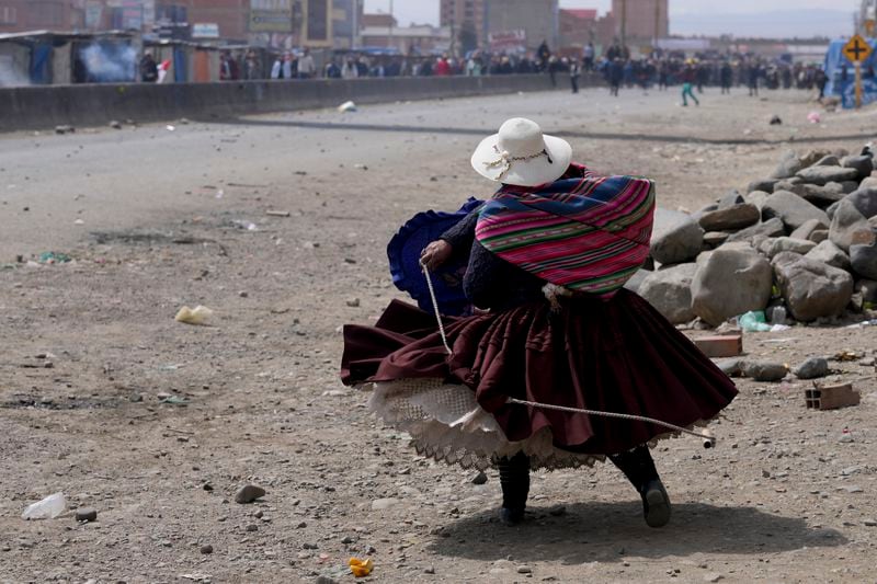 A supporter of former President Evo Morales throws a rock at supporters of current President Luis Arce in El Alto, Bolivia, Sunday, Sept. 22, 2024. (AP Photo/Juan Karita)