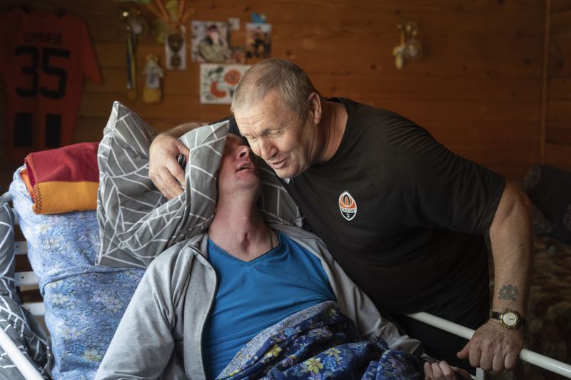 Serhii Shumei, 65, and his son Vitalii, 36, a Ukrainian officer heavily wounded in a battle with Russian forces, sing at the rehabilitation centre in Modrychi, Western Ukraine, Wednesday, Aug. 28, 2024. (AP Photo/Efrem Lukatsky)