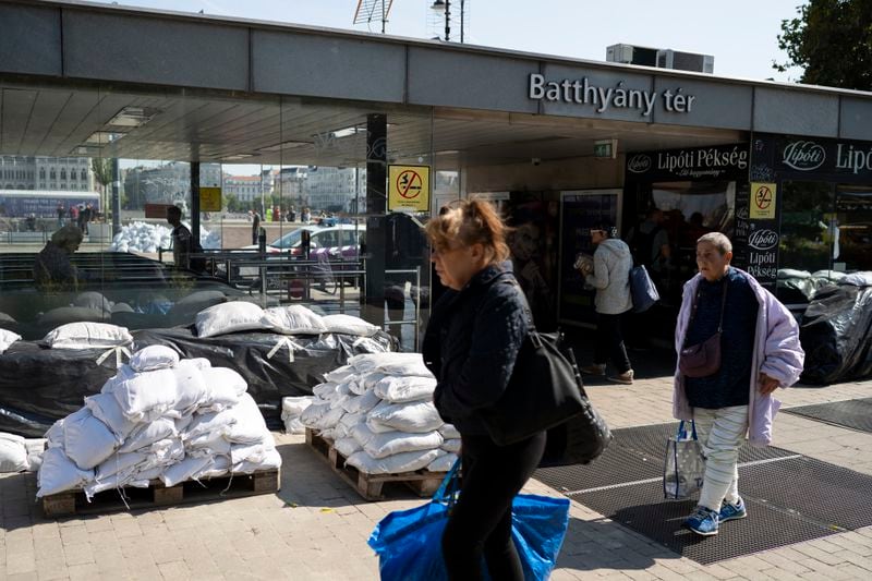 People walk next to a metro station surrounded by sandbags as the Danube river floods it's banks, central Budapest, Thursday, Sept. 19, 2024. (AP Photo/Denes Erdos)