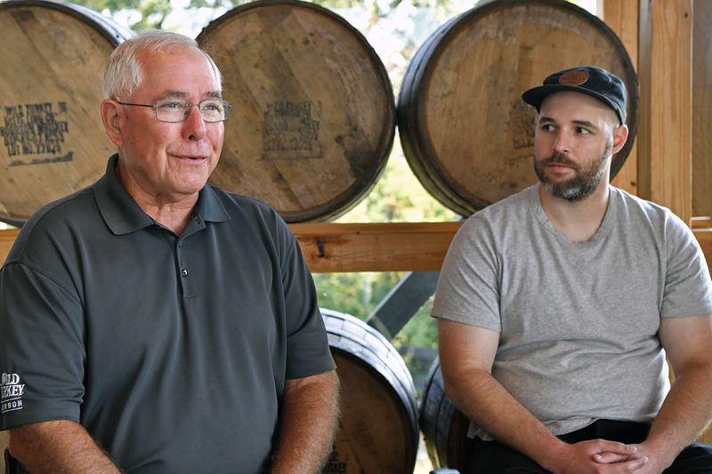 As his son Bruce Russell, right, looks on, Eddie Russell, master distiller, and son of 89-year-old Jimmy Russell, the "Buddha of Bourbon" talks about having three generations of the Russell family involved in the bourbon industry at the Wild Turkey Distillery in Lawrenceburg, Ky., Wednesday, Aug. 28, 2024. (AP Photo/Timothy D. Easley)