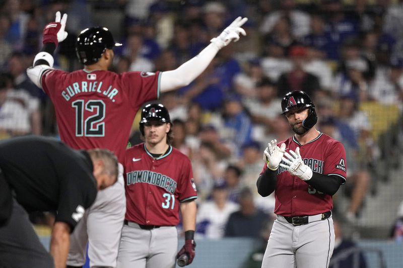 Arizona Diamondbacks' Lourdes Gurriel Jr., left, and Christian Walker, right, celebrate as Jake McCarthy watches after Gurriel Jr. hit a two-run home run during the sixth inning of a baseball game against the Los Angeles Dodgers Wednesday, July 3, 2024, in Los Angeles. (AP Photo/Mark J. Terrill)