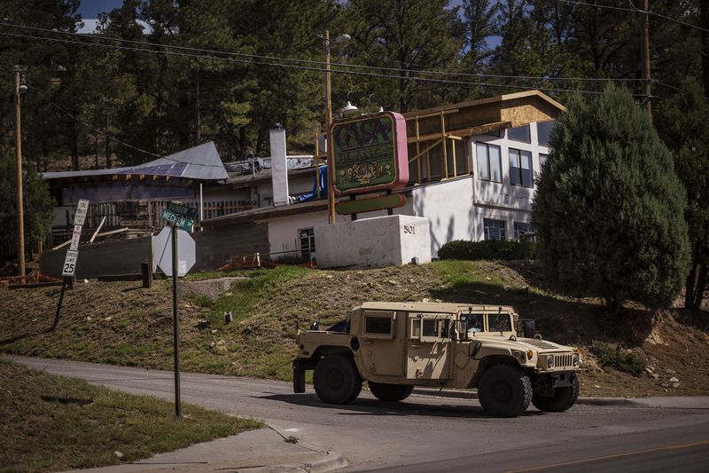 National Guard vehicles block roads to "no entry/ exclusion zones" that will remain inaccessible due to ongoing recovery operations after wildfires ravaged the mountain village of Ruidoso, N.M., Monday, June 24, 2024. (Chancey Bush/The Albuquerque Journal via AP)