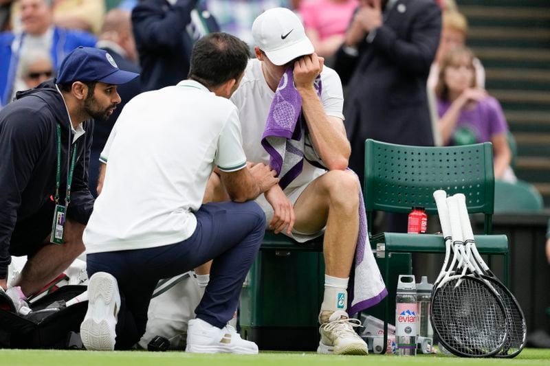 Jannik Sinner of Italy reacts as he receives treatment from a trainer during his quarterfinal match against Daniil Medvedev of Russia at the Wimbledon tennis championships in London, Tuesday, July 9, 2024. (AP Photo/Alberto Pezzali)