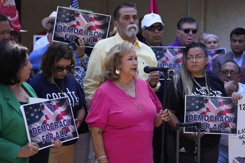 Lydia Martinez, a volunteer and great-grandmother whose home was searched, center, speaks at a news conference where she and officials with the League of United Latin American Citizens, or LULAC, responded to allegations by Texas Attorney General Ken Paxton, Monday, Aug. 26, 2024, in San Antonio. (AP Photo/Eric Gay)